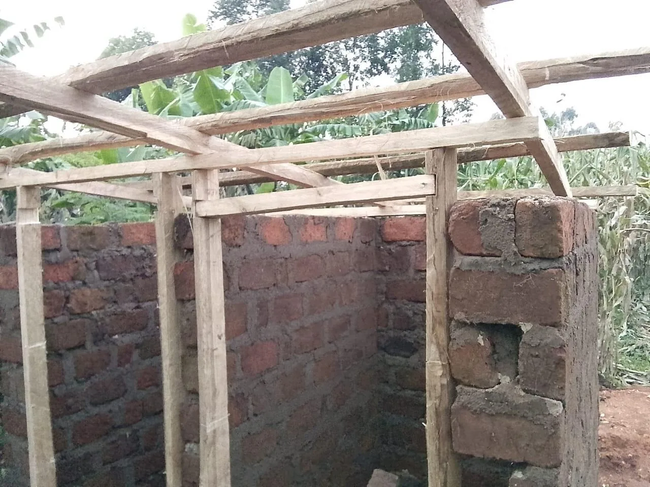 The church building under construction — brick walls and a timber roof frame